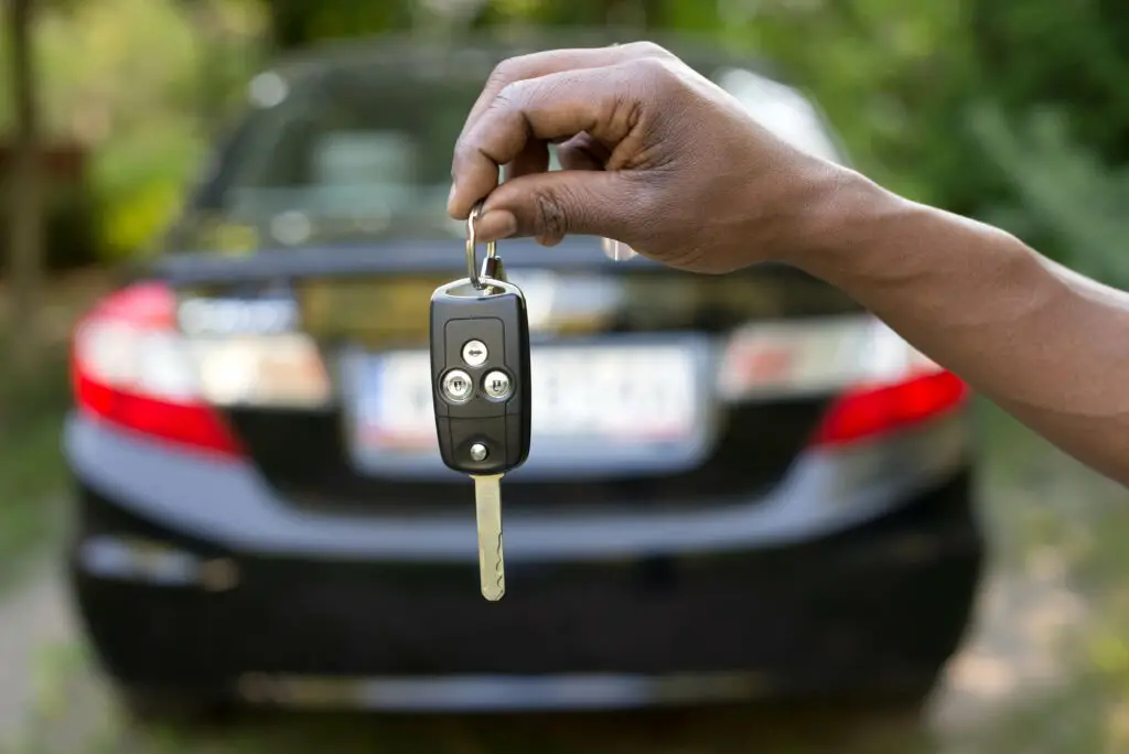 Car in background a hand holding key in front (1)
